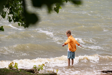 A boy in an orange shirt on the seashore