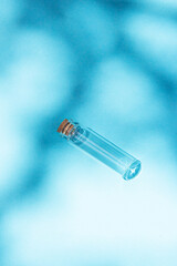Modern apothecary concept. Empty glass miniature bottle with cork cap on a blue background