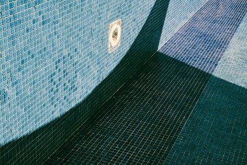 Empty pool with old blue cubic tiles in sunny weather