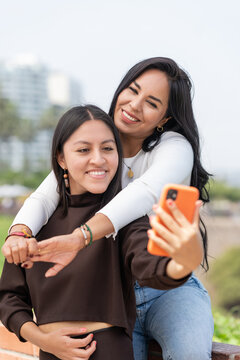 Lesbian couple embracing while taking selfie outdoors