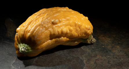 Fat and short yellow squash on a brown stone surface