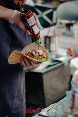 Vertical shot of a chef pouting ketchup on tacos during a food festivel