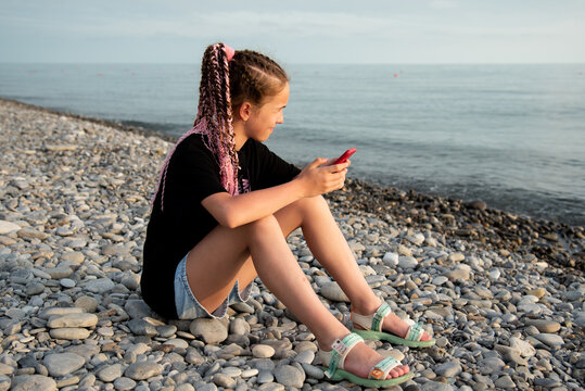 The girl sits and communicates online. Communication. Generation Z. Recreation. Sea.