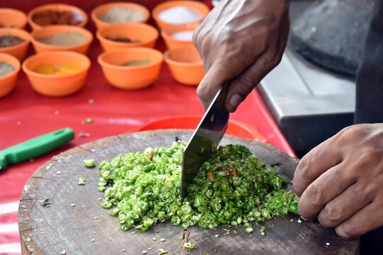A Chaf slicing Chili pepper with Knife on wooden board
