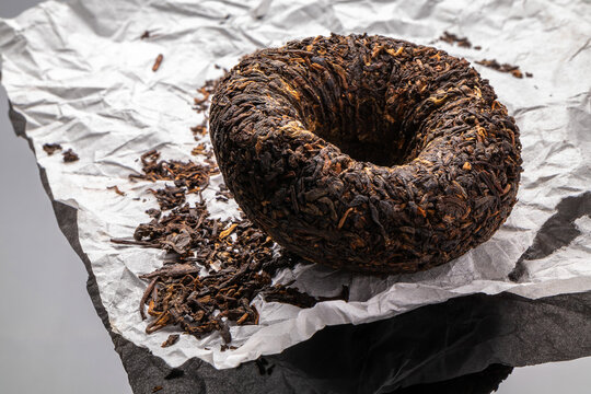chinese puerh tea form of a bowl with wrapping paper on a black mirror background