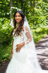 beautiful african-american bride standing in white gown outdoors in nature