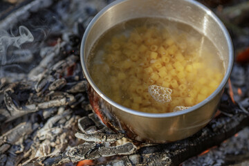 Cooking food in pot on campfire..The concept of adventure, travel, tourism, camping, survival and evacuation.