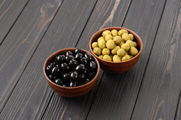 Black and green olives on a dark wooden rustic background.