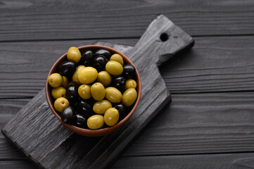 Black and green olives on a dark wooden black background.