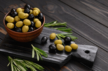 Black and green olives on a dark wooden rustic background.