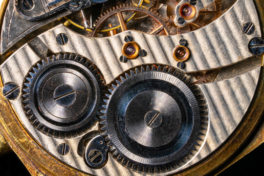 Rear viev of a old pocket watch with an open clockwork on black isolated background. Retro clock, inside view of gearing, gears. Mechanism of mechanical golden vintage watch close up.
