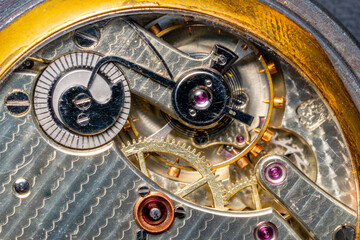 Fototapeta na wymiar Rear viev of a old pocket watch with an open clockwork. Retro clock, inside view of gearing, round wheel gears. Mechanism of mechanical golden vintage watch close up.