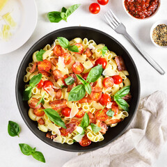 Tomato and bacon pasta with parmesan cheese and basil leaves