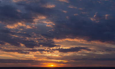 Landscape with bloody sunset. Panorama. Tragic gloomy sky. The last flashes of the sun on the storm clouds.