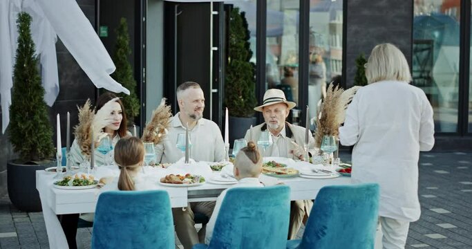 Mature woman treats relatives to meal at festive table