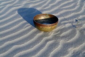 A singing bowl on a sandy beach. English translation of mantras. transform your impure body