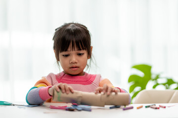 Little Asian girls are making tissue paper core binoculars. Reuse waste products. Idea custom made toy. Soft focus.