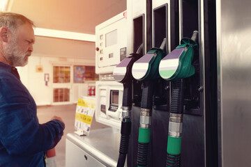 A man at gas station paying for fuel before filling tank of his car with fuel to the top level as...