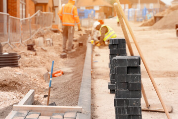 Builders installing paving blocks during road and footpath construction on a semi-dray concrete mix. Block paving footpath in progress