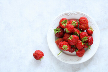 strawberries on a plate on a light surface.