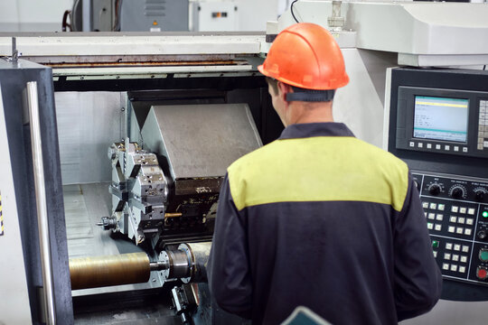 Experienced worker changing tool setup of cnc lathe machine on the factory floor