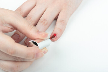 A woman applies polish to her little fingernail.