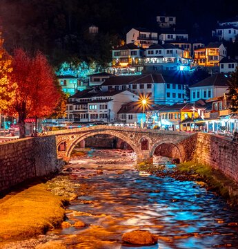 River with a stone bridge in downtown Prizren with buildings and trees at night, Pristina Kosovo