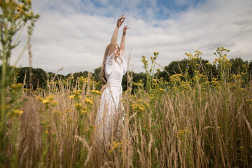Summer portrait of woman in white dress dancing in the field