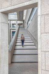 Person walking alone up a long set of granite stair steps in a granite and concrete building