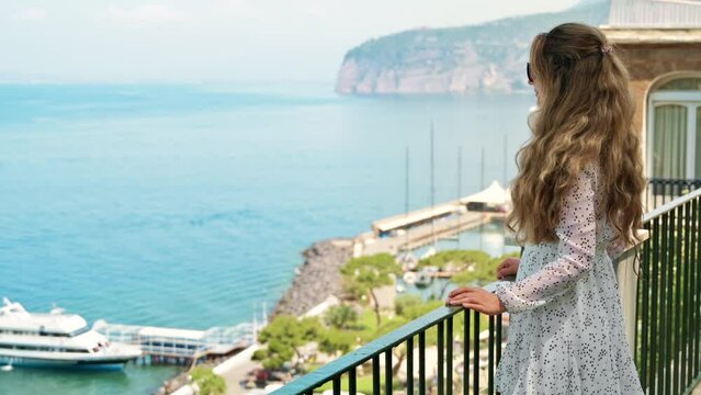 View of a blonde woman posing on the Tyrrhenian sea coast in Sorrento, Italy
