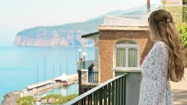 View of a blonde woman posing on the Tyrrhenian sea coast in Sorrento, Italy