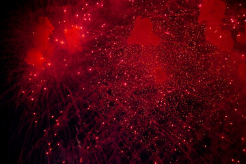 A bright firework with a red glowing center with red sparks and smoke flying towards the background...