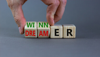 Winner or dreamer symbol. Concept words Winner or dreamer on wooden cubes. Businessman hand. Beautiful grey table grey background. Business and Winner or dreamer concept. Copy space.