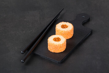 Apricot mousse dessert, in the form of round sweet sushi, on a serving board. Dark gray background