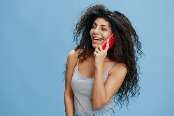 ONLINE CALL AD CONCEPT. Laughing beautiful curly Latin lady hold pink smartphone in hand, talk...