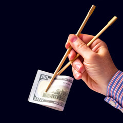 hand holds dollars with bamboo chopsticks on a dark background. financial industry in food. cash spending concept
