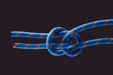 durable colored rope for climbing equipment on a dark background. knot of braided cable. item for tourism and travel