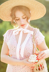 Close up portrait of a sweet blonde in a straw hat at the sunset