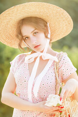 Close up portrait of a sweet blonde in a straw hat at the sunset