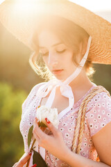 Close up portrait of a pretty blonde girl in a straw hat at the sunset