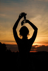 Close up silhouette of a woman with a flower in her hands at sunset. Image against the sun and...