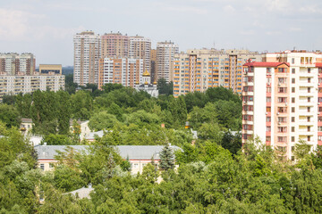 Panoramic urban landscape - modern high residential buildings among green trees on a cloudy summer day