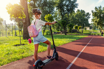 Profile view portrait of cute blond little caucasian school girl wear helmet enjoy having fun riding electric scooter city street park outdoors on sunny day. Healthy sport children activities outside © Kyryl Gorlov