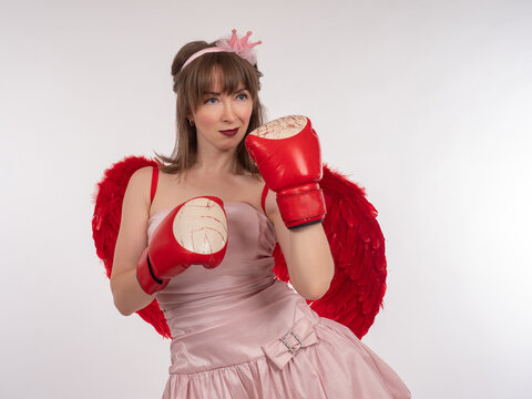 Portrait of beautiful woman in boxing gloves. Concept is strong and independent woman. Portrait of a strong woman on white background. Boxer girl in pink dress. Girl boxer in red gloves.