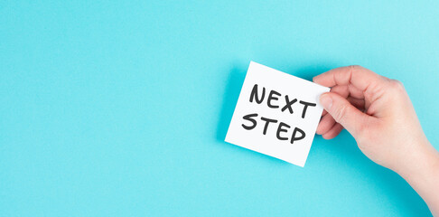 The phrase next step is standing on a paper, having new goals and strategies, making plans for future
