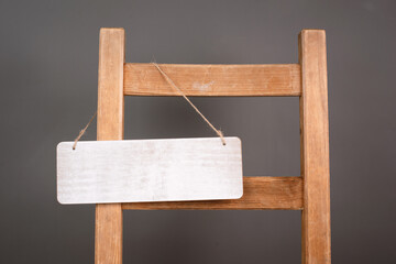 Blank wooden sign is hanging on a chair, welcome and sale concept, copy space for text, open and closed business

