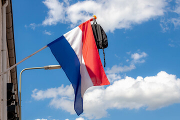 Official Netherlands flag with a school bag hanging outside the house along the street with blue sky, A tradition way in Holland when a student celebrate their graduates or Geslaagd in Dutch word. - obrazy, fototapety, plakaty