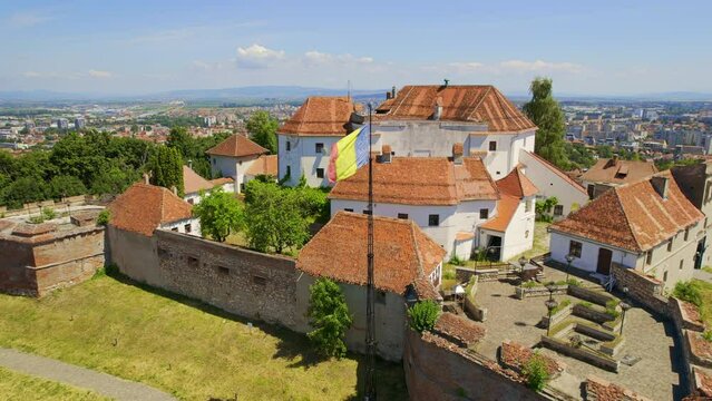 Aerial drone view of The Citadel in Brasov, Romania. Medieval fortress on the top of a hill. Buildings, green trees