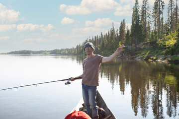 A man fishing with a fishing rod on the river in summer.