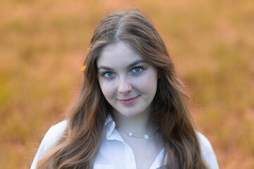 Naklejka premium Portrait of a beautiful girl with red hair and freckles on her face in an autumn park.